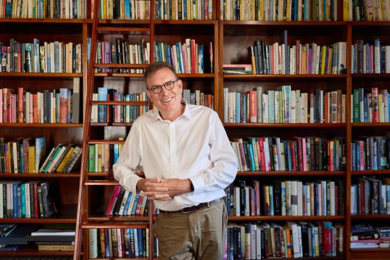 A man standing with books shelf behind him
